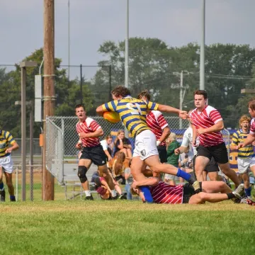 Two rugby teams chase each other on the pitch.