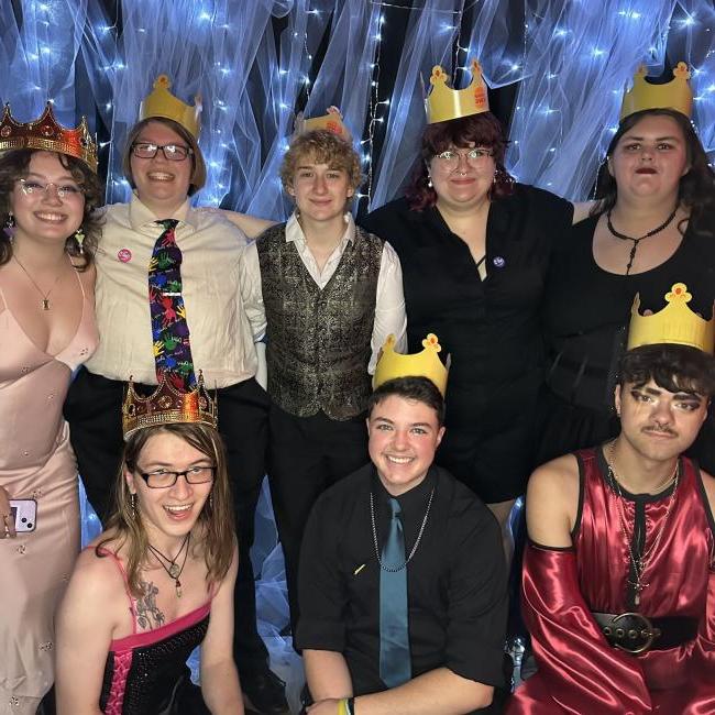 A group of students wearing crowns smile for the camera. 